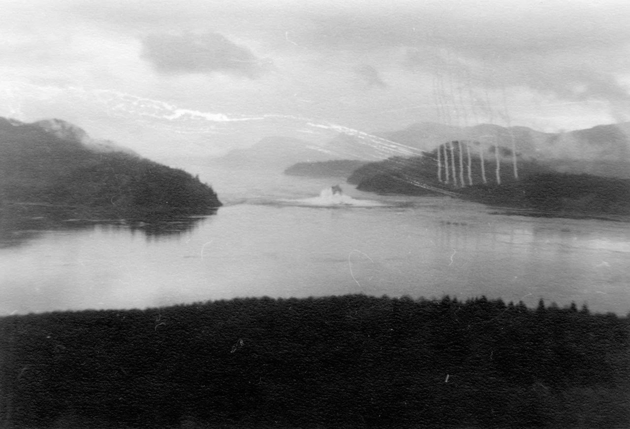 Item is a photograph of the blasting of Ripple Rock, the navigational hazard in the Seymour Narrows, from a bunker position on an area hilltop. This was taken immediately following detonation, with the blast cloud having just broken through the surface of the water.