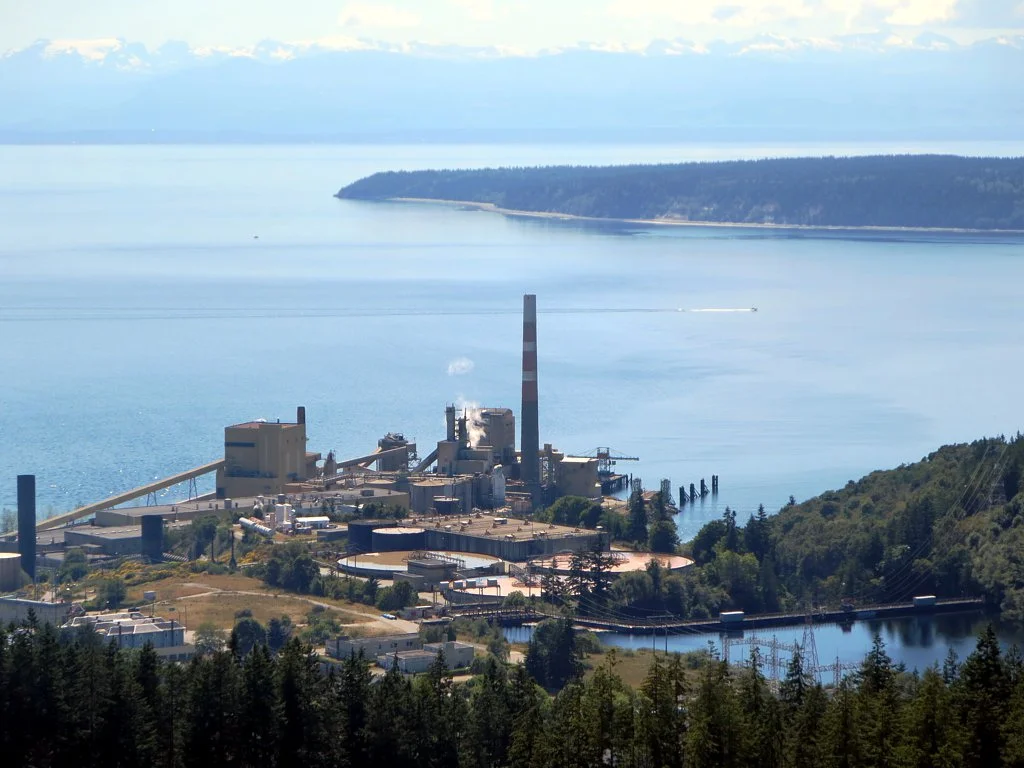 The Catalyst Paper Mill (1910) at Powell River, British Columbia, was the first and largest newsprint manufacturer in Western Canada. The Powell Lake Dam is on the right.