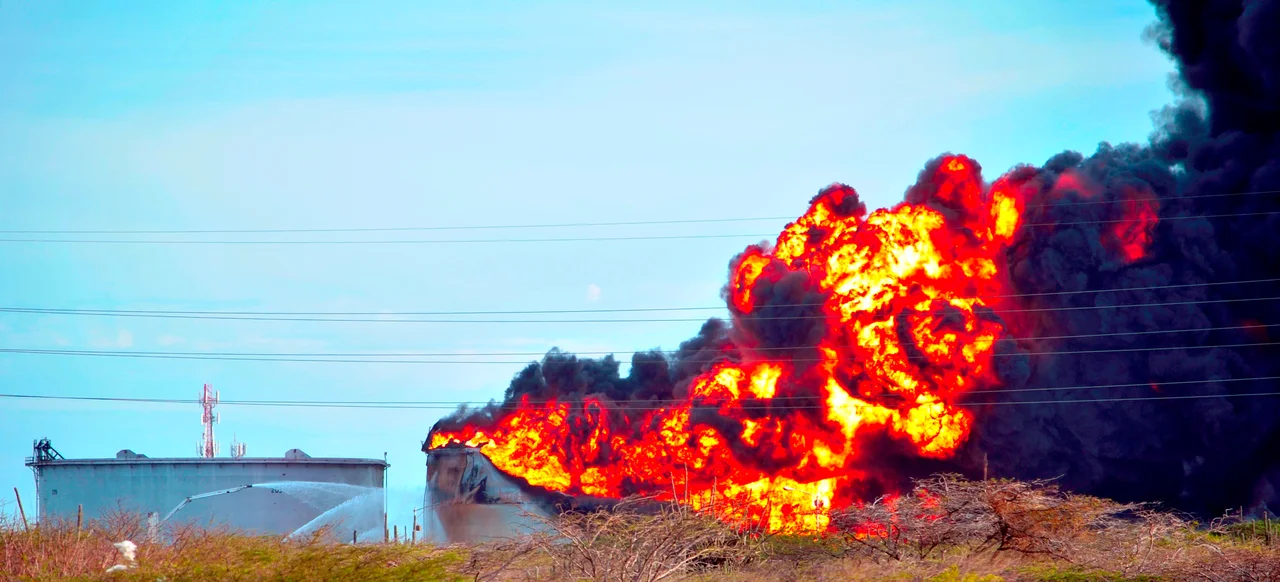 Tanque de hidrocarburo siendo enfriado con espuma por cañones de alta presión.