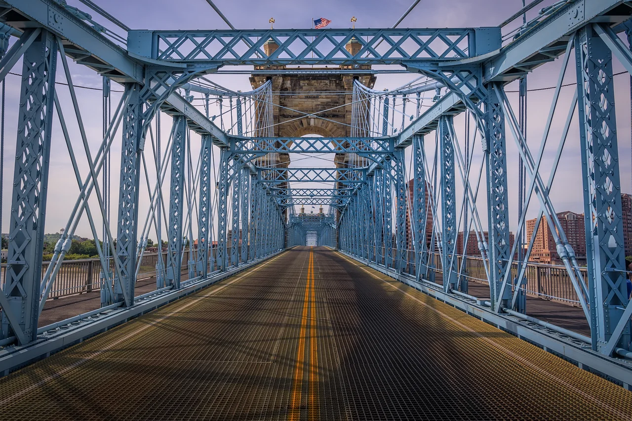 The John A. Roebling Suspension Bridge, originally known as the Cincinnati-Covington Bridge spans the Ohio River between Cincinnati, Ohio and Covington, Kentucky. When opened on December 1, 1866, it was the longest suspension bridge in the world at 1,057 feet (322 m) main span[3], which was later overtaken by John A. Roebling's most famous design of the 1883 Brooklyn Bridge at 1,595.5 feet (486.3 m). Pedestrians use the bridge to get between the sports venues in Cincinnati (Paul Brown Stadium, Great American Ball Park, and U.S. Bank Arena) and the hotels, bars, restaurants, and parking lots in Northern Kentucky. The bar and restaurant district at the foot of the bridge on the Kentucky side is known as Roebling Point.