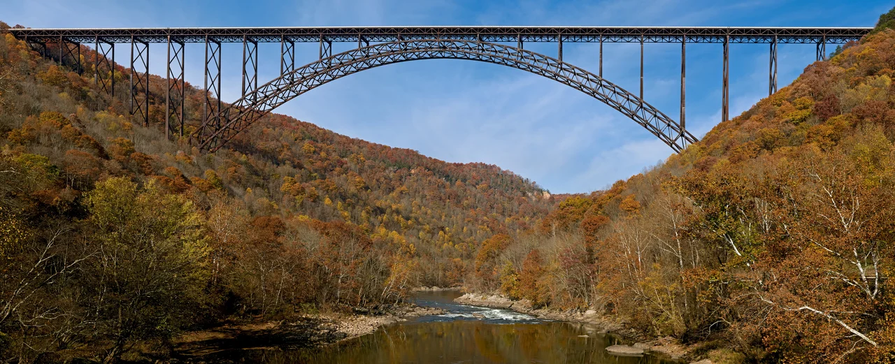 The New River Gorge Bridge in Fayetteville, West Virginia is a steel arch bridge that carries US 19 over the New River. It opened in 1977 and is the longest and highest steel arch bridge in the Western Hemisphere at 3030 ft (924 m) long and 876 ft (267 m) high. The bridge hosts Bridge Day, an annual event in which it closes to vehicles, and participants are allowed to BASE jump to the valley floor below.