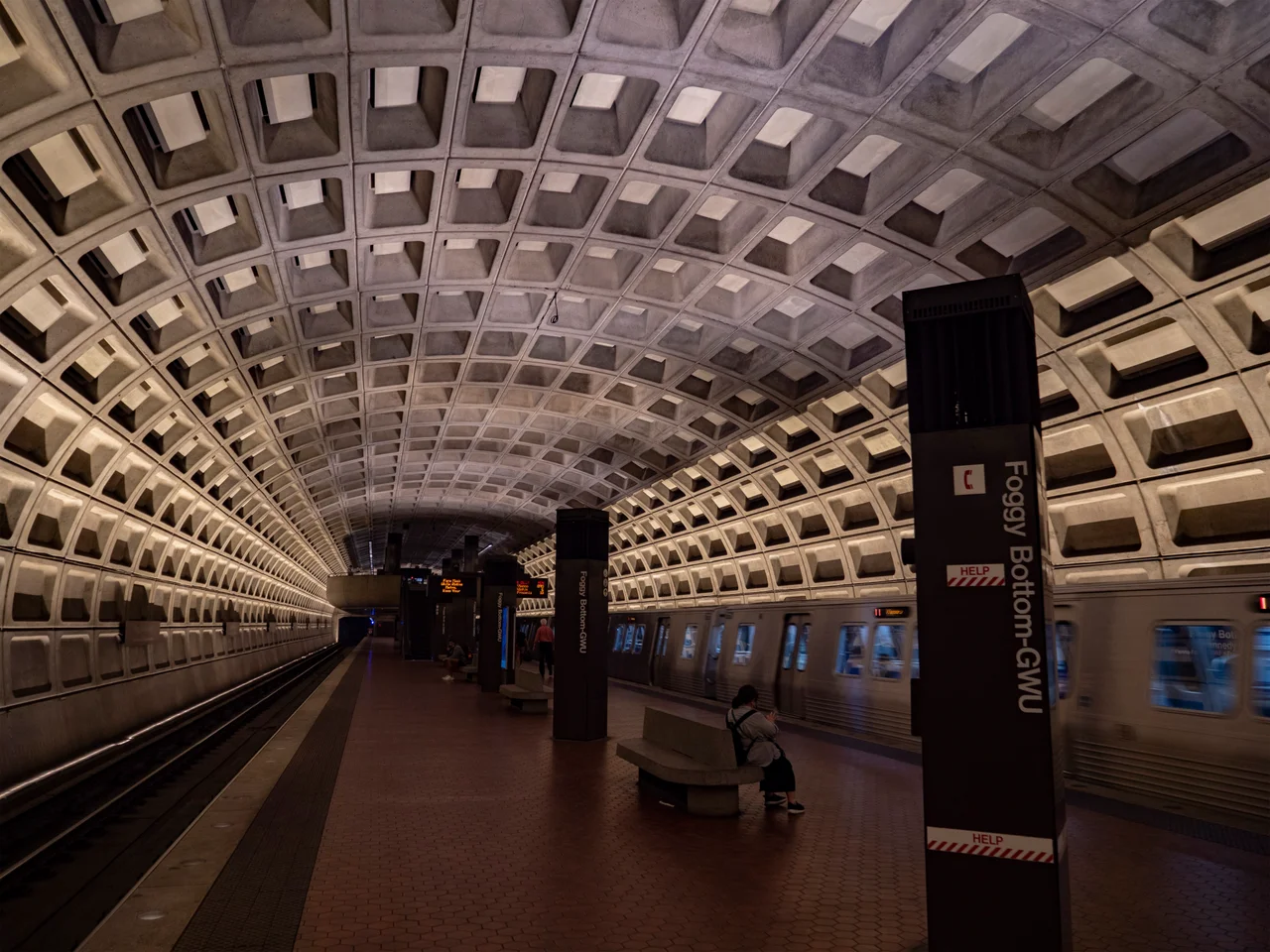 View facing west at the WMATA Foggy Bottom–GWU station. A 7000 series Orange Line train to Vienna/Fairfax is departing.