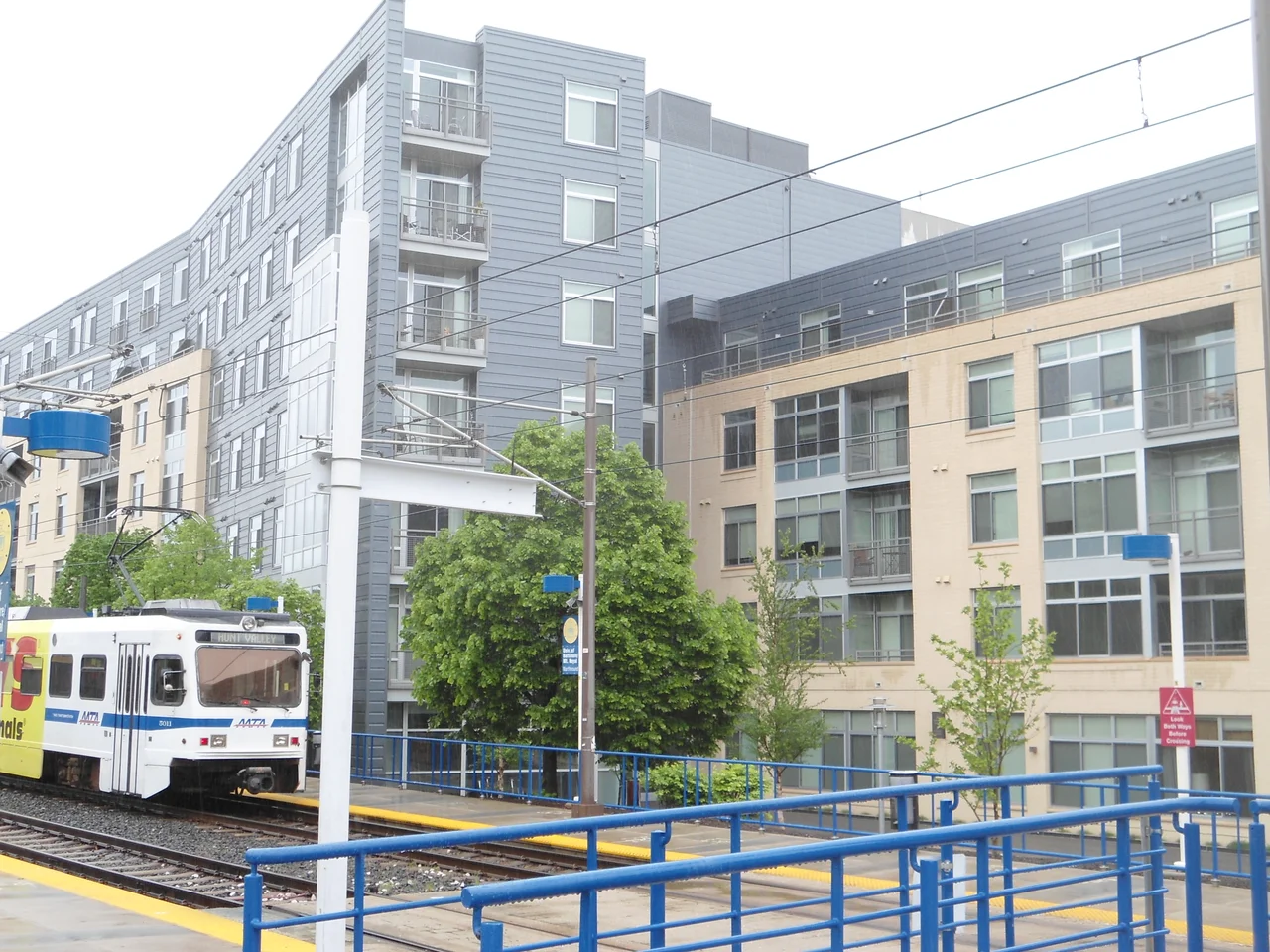 A train on Baltimore Light Rail's blue line at the University of Baltimore stop. In the background is the Fitzgerald building, one of two new student housing centers at the university.