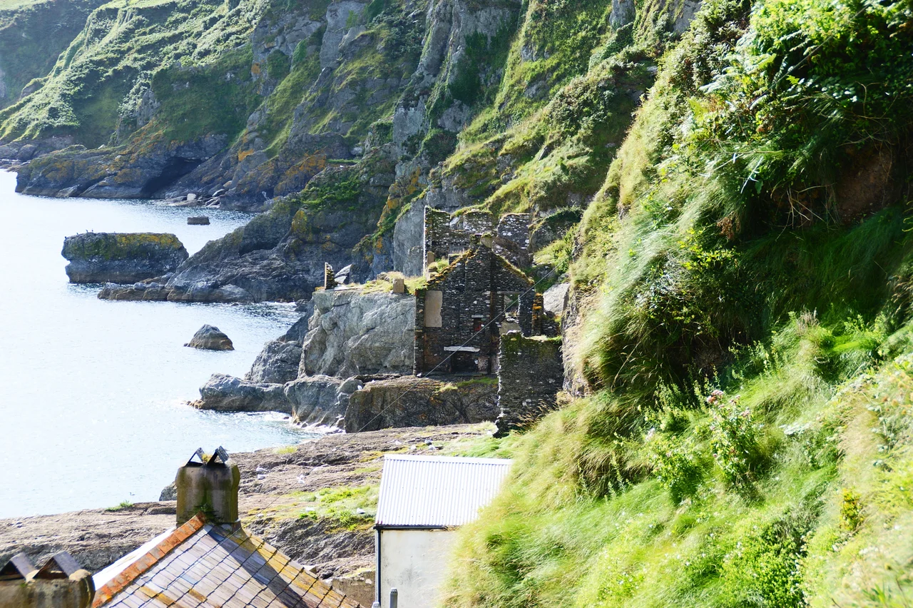 This shows some of the ruined buildings on the edge of the sea at Hallsands in Devon. The village has been partly destroyed by the sea. The buildings in the foreground (roofs of) are still occupied.