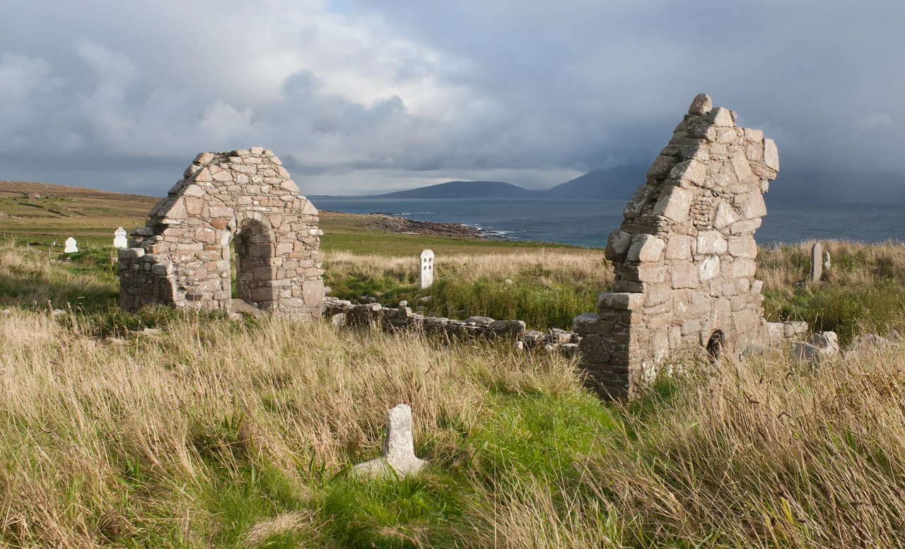 North-west view of Teampall Deirbhile (St. Dervla's Church) in the evening sun with the Blacksod Bay and Achill Island in the background.
