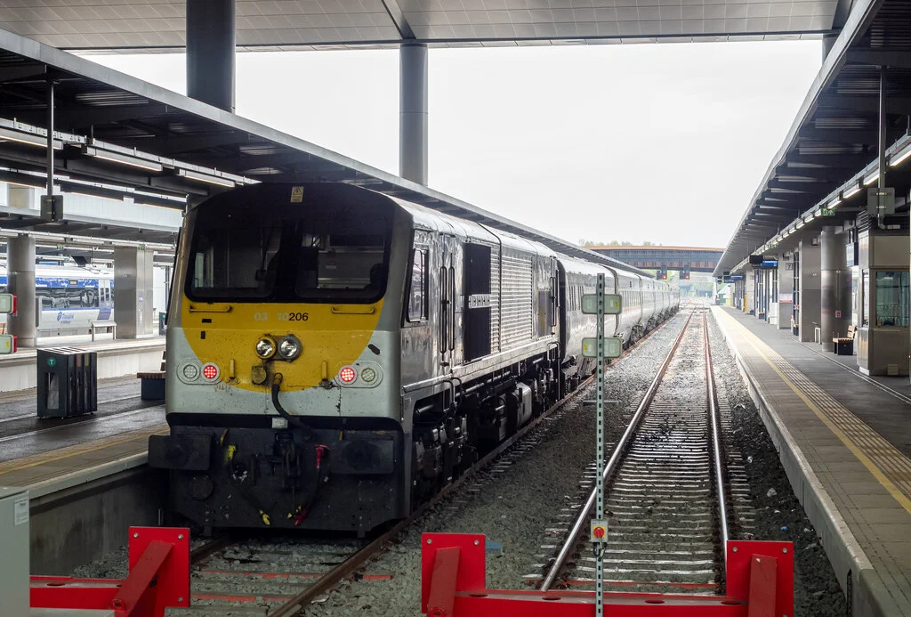 A locomotive hauled Belfast-Dublin 'Enterprise' service awaits departure, propelled by IÉ 201 class Abhainn na Life / River Liffey. All Belfast-Dublin services moved from Lanyon Place station when Grand Central opened; services were also increased to hourly from bihourly. To accommodate the increase in services, a variety of rolling stock from IÉ and NIR is used.