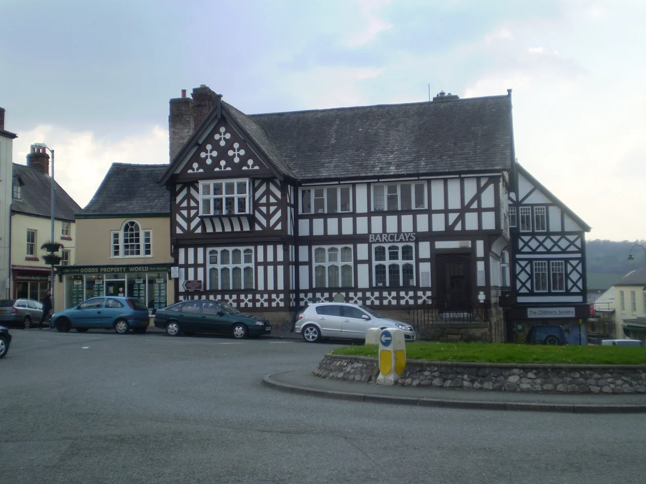 Exmewe Hall (previously Barclays Bank) on St Peter's Square, Ruthin, Wales, is the ancestral home of Sir Thomas Exmewe, Lord Mayor of London in 1517-18. Maen Huail, the stone upon which legendarily King Arthur beheaded his rival-in-love Huail, is behind the silver car.