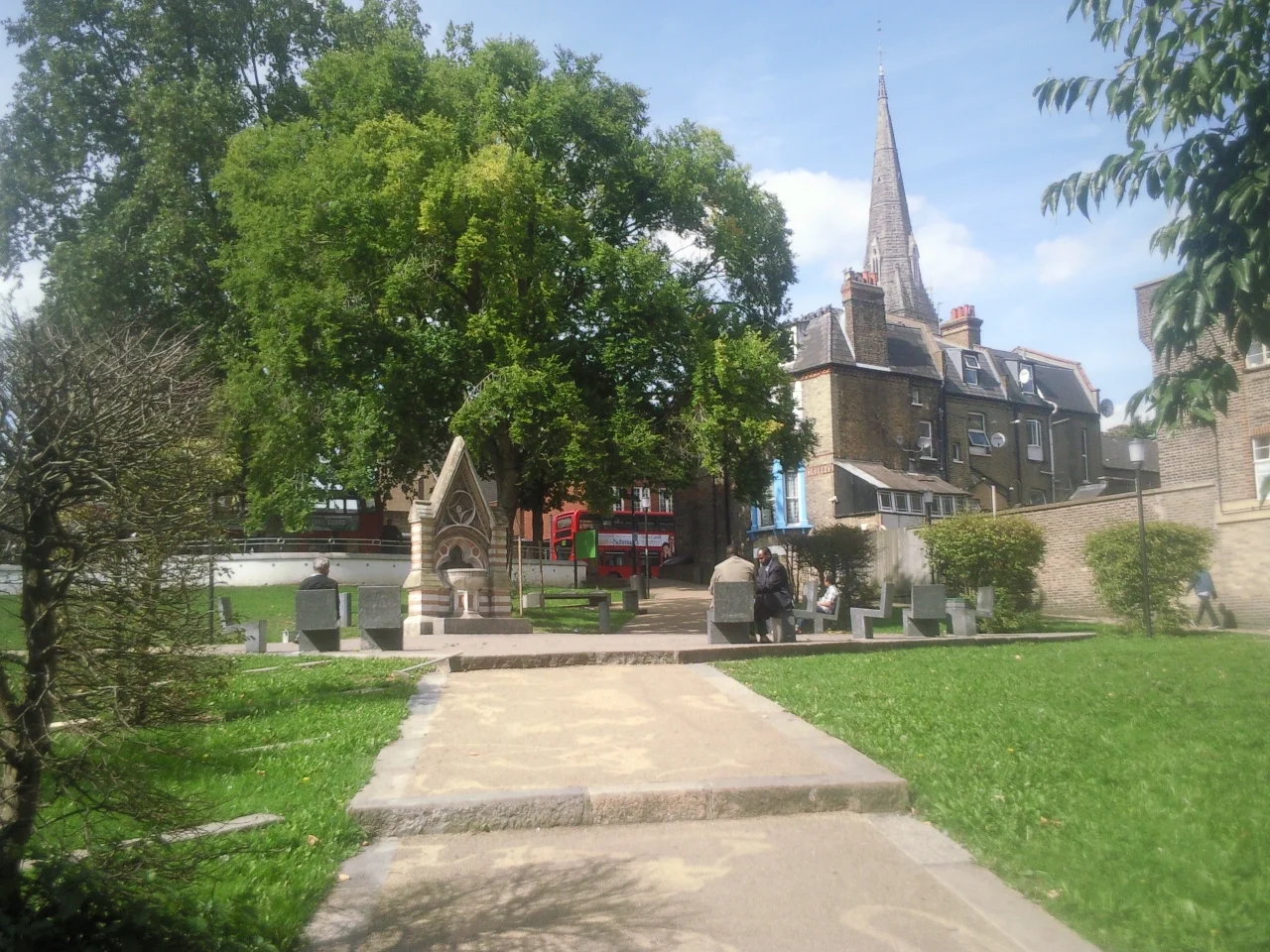 Part of Streatham Green, London SW16, looking north to the Dyce Drinking Fountain (left) and spire of the Roman Catholic church of the English Martyrs. The Dyce Fountain was moved here in 1933 from Streatham High Road.