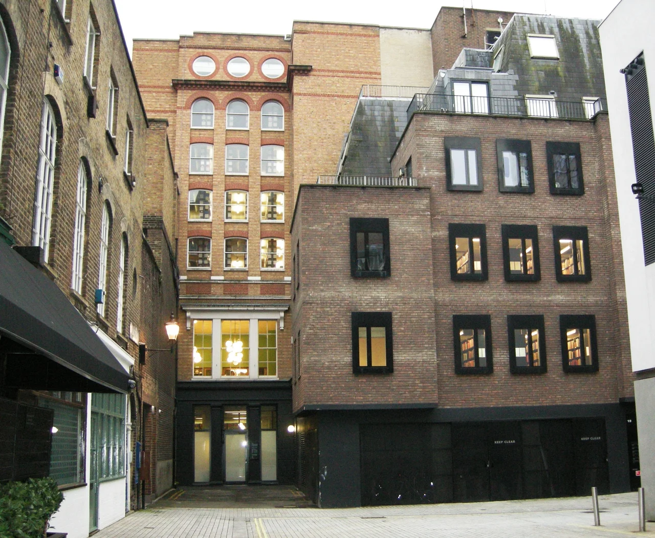 View of London Library premises from the north (Mason's Yard, St James's, London). The large windows at first floor level in the blind alley to the left belong to the north bay of the Reading Room; the five storeys above are bookstack added in 1992. The brown brick building to the right is T.S. Eliot House, acquired in 2004.