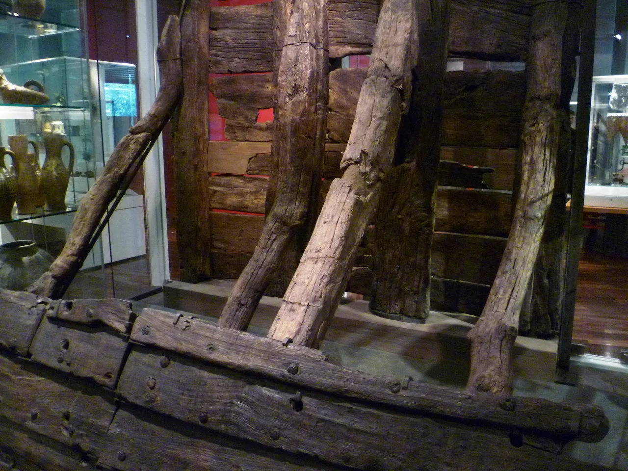 Part of a retaining wall of oak timbers from the Thames riverbank at Billingsgate, excavated in 1982. The diagonal braces extended into the river to support the vertical posts and horizontal planks. An exhibit in the Museum of London.