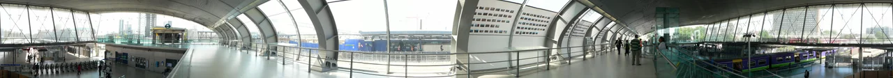A 360° panoramic image of the low level part of Statford station in London. The photos were taken from the walkway from the adjacent high-level station (which can be seen through the windows in the middle of the image).
This image is composed of 11 individual photographs that I took myself on 16 August 2008 from almost exactly the same place that I took the images for Image:Stratford station 13.jpg on 24 October 2005. Differences to note include the new Docklands Light Railway platforms have been constructed (see the left of the image), the additional westbound Central Line platform is being built (through the window in the left-centre of the image) and the "Platform for Art" exhibition on the walkway.
The train in the low-level platform is a North London Line service operated by London Overground and is about to commence its journey to Richmond. In the 2005 image this platform was an intermediate westbound stop on the Silverlink-operated North Woolwich to Richmond North London Line. From 2009 the North London Line will move to new platforms on the far side of the high level station, and the low level platforms will then be converted to form the penultimate stop on the new Canning Town to Stratford International branch of the Docklands Light Railway.
the same view in 2005.
The individual photographs that make up this merged image will be uploaded to Commons in the next couple of days, and linked from here.
