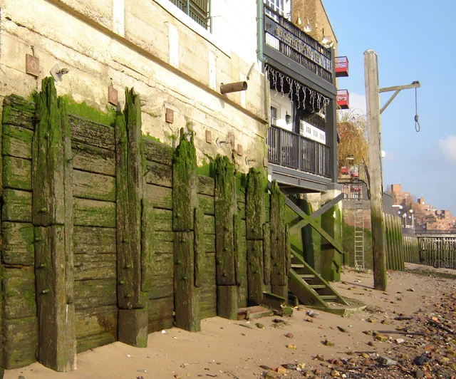 Thames foreshore at Wapping, Tower Hamlets, London, showing Execution Dock gibbet. The Prospect of Whitby is to the left. 6 January 2006. Photographer: Fin Fahey.