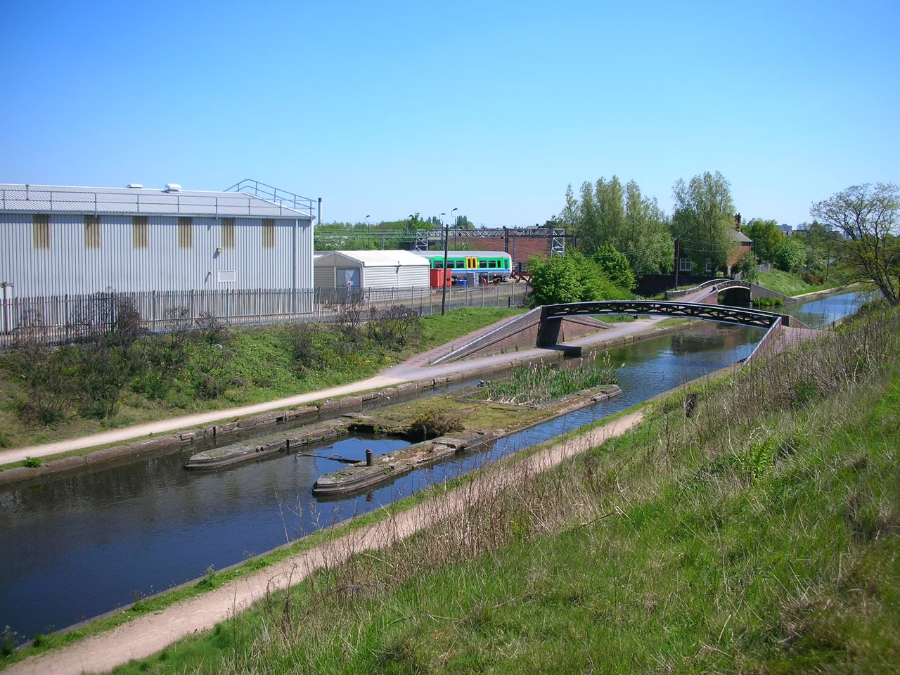 The derelict toll island in the, originally busy, double towpathed, Birmingham New Main Line Canal near Winson Green Junction, just outside the City of Birmingham boundary, England. 
A photograph in (Birmingham's Canals, Ray Shill, 1999, 2002, ISBN 0-7509-2077-7) shows an octagonal toll building with a plank across one channel for access by staff and also the artificial embankment (from where this photograph was taken) whose sole purpose was to carry the feeder channel from Rotton Park Reservoir to the Engine Arm at the higher Wolverhampton Level.
The wide iron roving bridge (made at Horseley Ironworks) allows a towing horse to cross the Main Line and pass under the smaller roving bridge and then enter the Soho Branch (part of James Brindley's Old Main Line canal).
Photographed by me 1 May 2007.

Oosoom 20:09, 19 May 2007 (UTC)