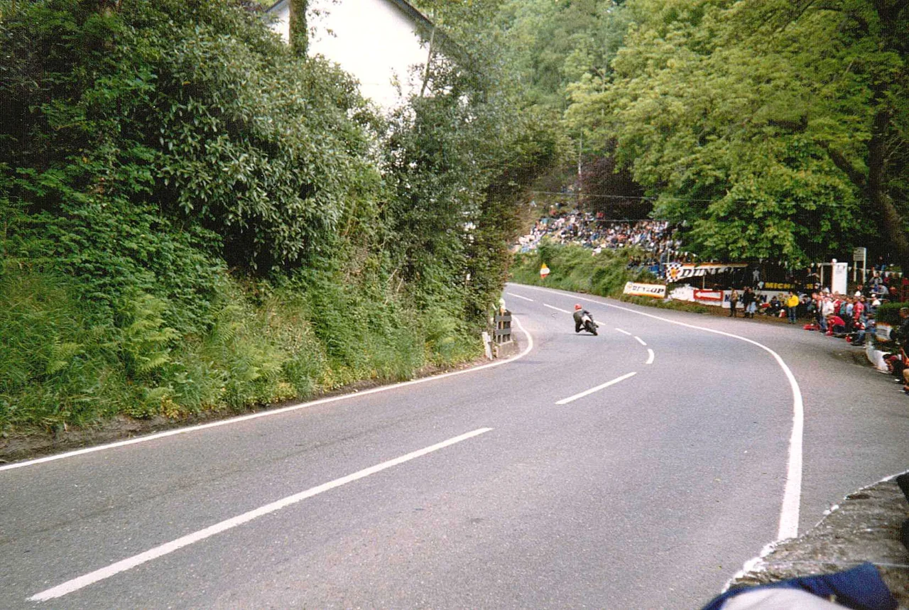 Geln Helen, a sweeping left bend exiting uphill, on the Snaefell Mountain Course in the countryside of the Isle of Man, immediately preceding Creg Willey's Kill and Sarah's Cottage