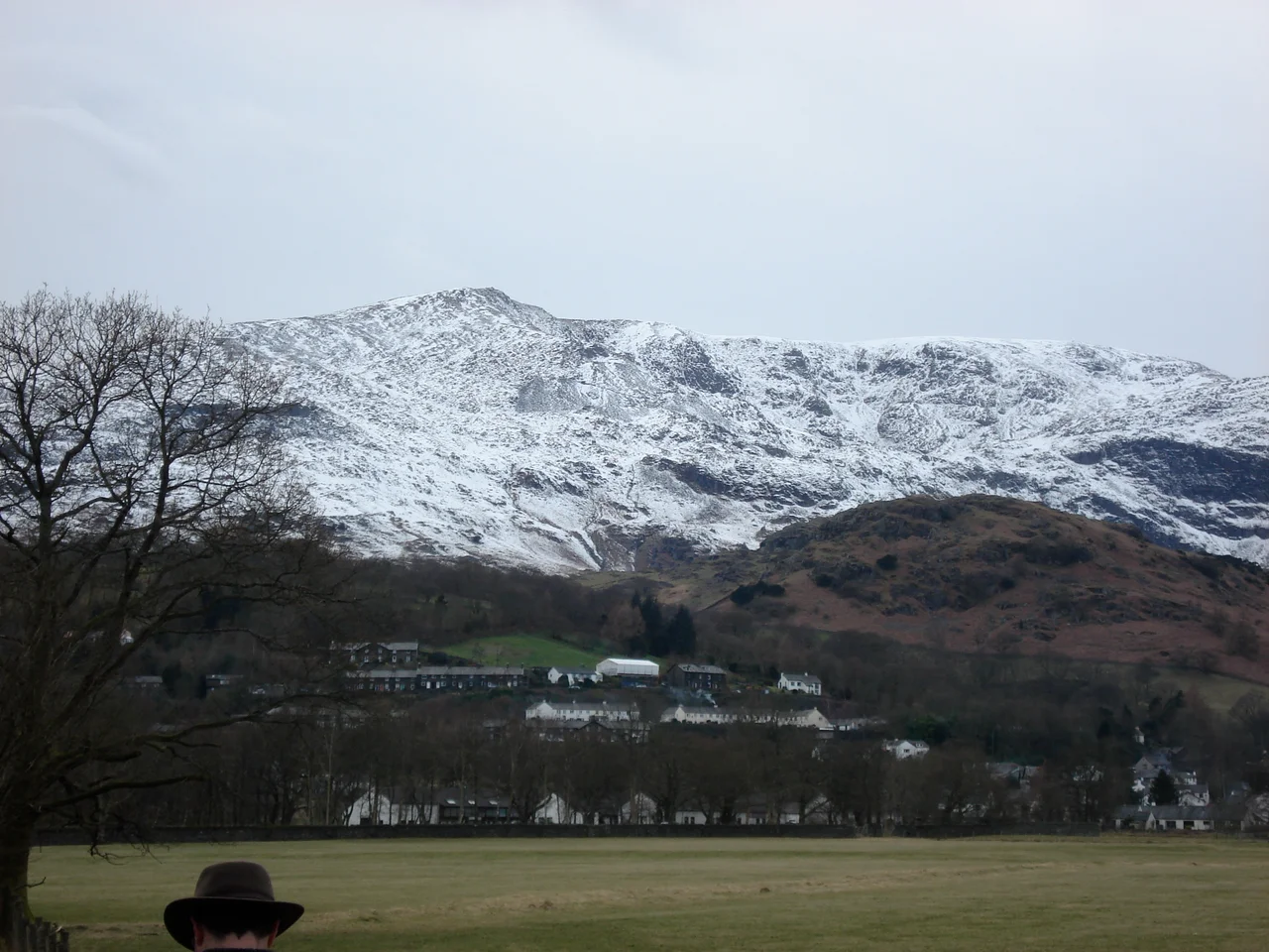 background: A mountain behind the village of Coniston foreground: Empty Feild