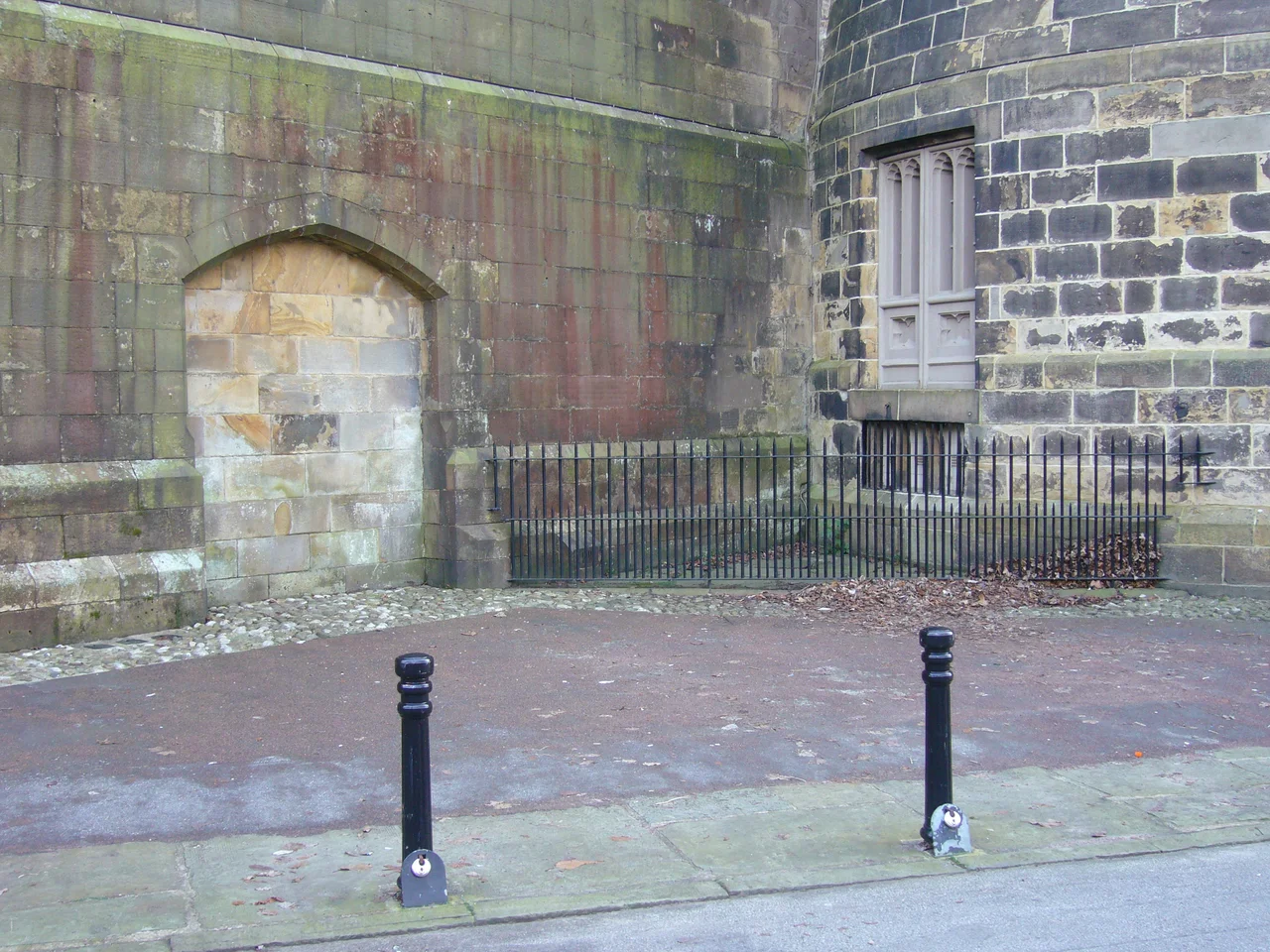 "Hanging Corner" outside Lancaster Castle, site of numerous public executions between the late 18th Century and 1865. The double-doors on the RHS hinged inwards into the "drop room", where condemned prisoners were pinioned immediately prior to execution. Condemned prisoners were led outside onto the wooden gallows platform, which was level with the bottom of the double-doors. The iron railings and bollards are modern additions made in the 20th Century.
