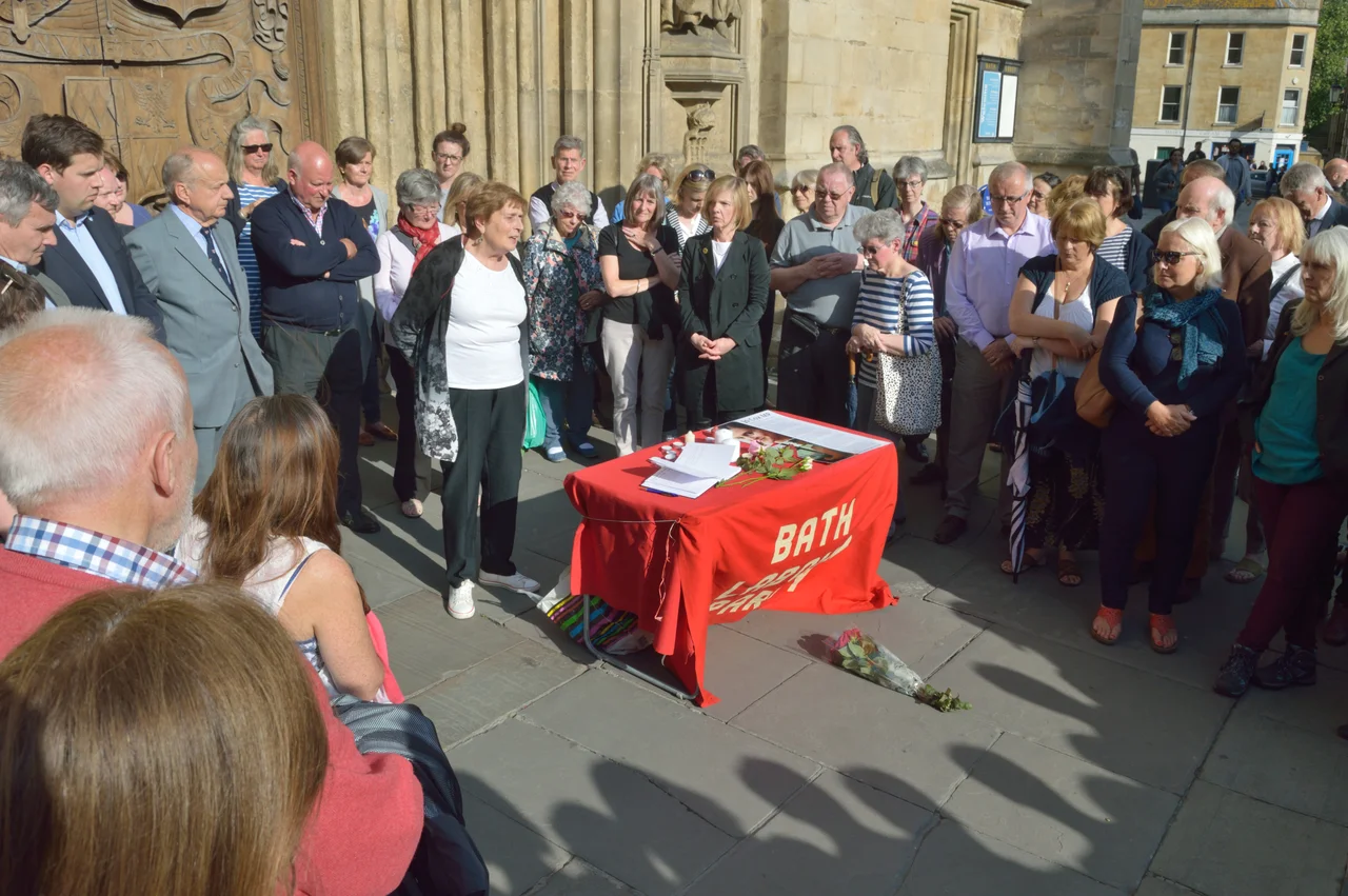 A tribute being made at the vigil for Jo Cox MP outside Bath Abbey on 18 June 2016, organised by Bath Labour Party.[1] Diana Page of the Bath Labour Party is giving the tribute, and vigil organiser Jane Middleton, Chair of Bath Labour Party, is standing to her left. Bath MP Ben Howlett, of the Conservative Party, can be seen in upper left of photo. A book of condolences for after the tributes can be seen on the table.