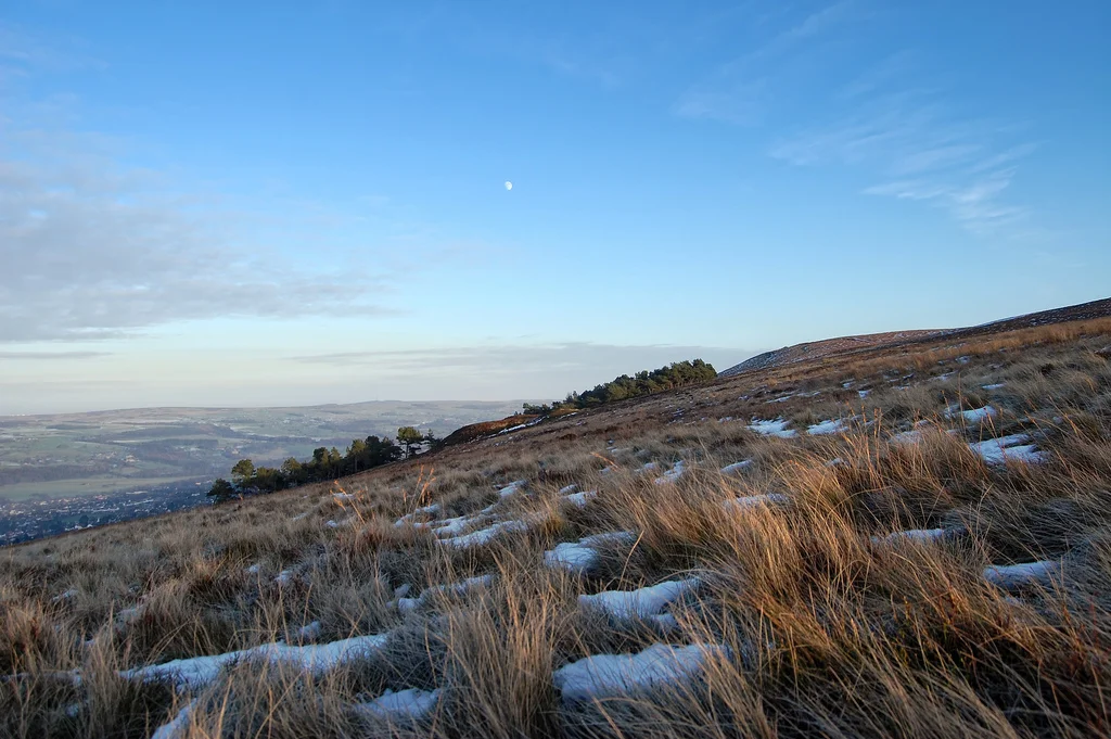 Dying rays of sunlight momentarily breathe warm colours into the browbeaten grass of a wintry Ilkley Moor on a clear evening as the daylight falls. The original image can be found in full resolution at this address.