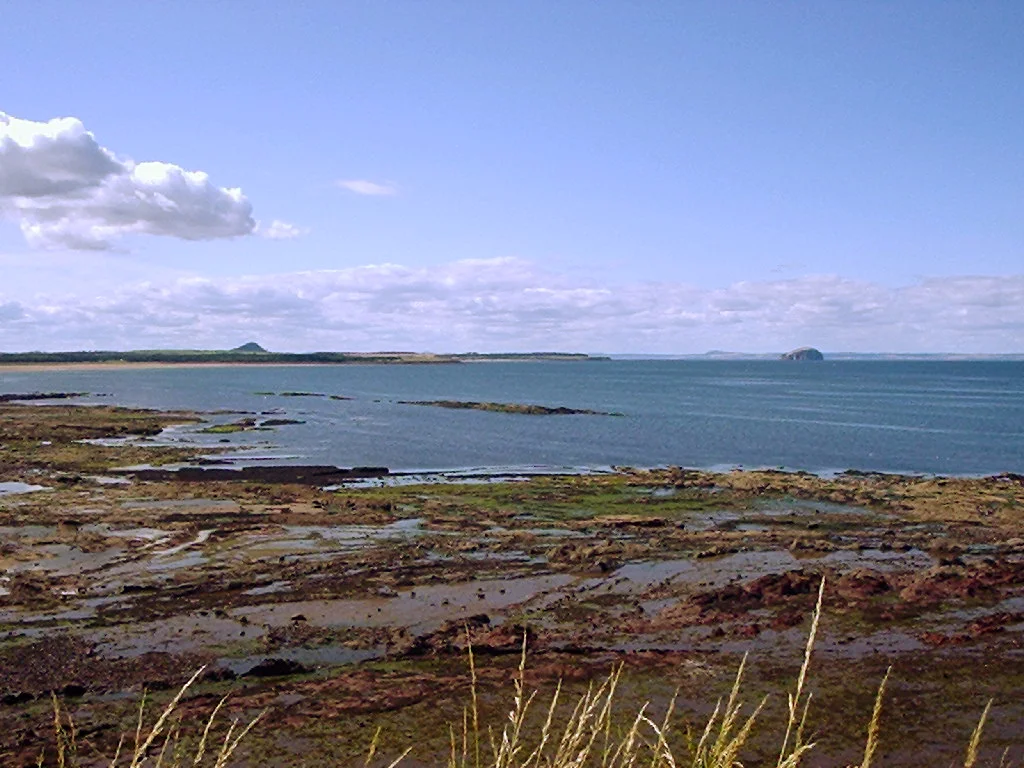 View north-west from John Muir Country Park towards Belhaven Bay with North Berwick Law and Bass Rock in the distance.