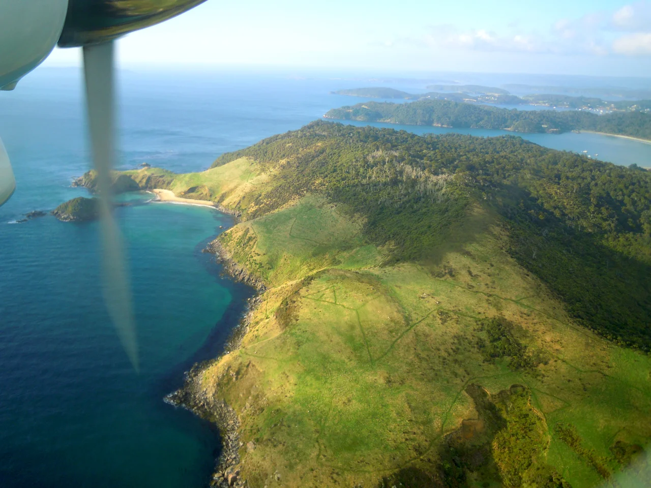 This photo was taken out of a window on a plane to Stewart Island in New Zealand. On the photo is Lee Bay first, then Horseshoe Bay behind that, and in the back you can see the opening of Halfmoon Bay.