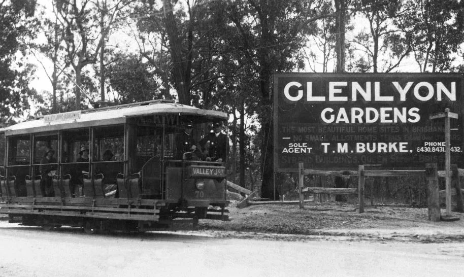 Tramdrivers and passengers in a Valley Junction tram at Ashgrove in 1923, on the corner of the Glenlyon Gardens housing estate. The agent's sign (T. M. Burke) is prominent against a background of trees.