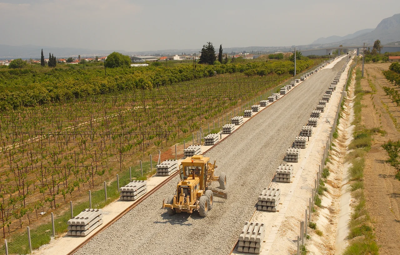 Bahnstrecke (Athen)-Korinth-Patras, 2007 am Golf von Korinth, in der Ebene der Präfektur Konrinthia. Die fruchtbare Landwirtschaftsfläche steht unter massivem Siedlungsdruck. Die Verkehrsinfrastruktur wird gerade erst aufgebaut.
Railway line (Athens)-Korinthos-Patras, 2007, Konrinthiakos Gulf. Coastal plane of Prefecture Korinthia. Urban settlements infiltrate the farming areas rapidly. Trafficstructure (roads and public transport) lacks far behind.