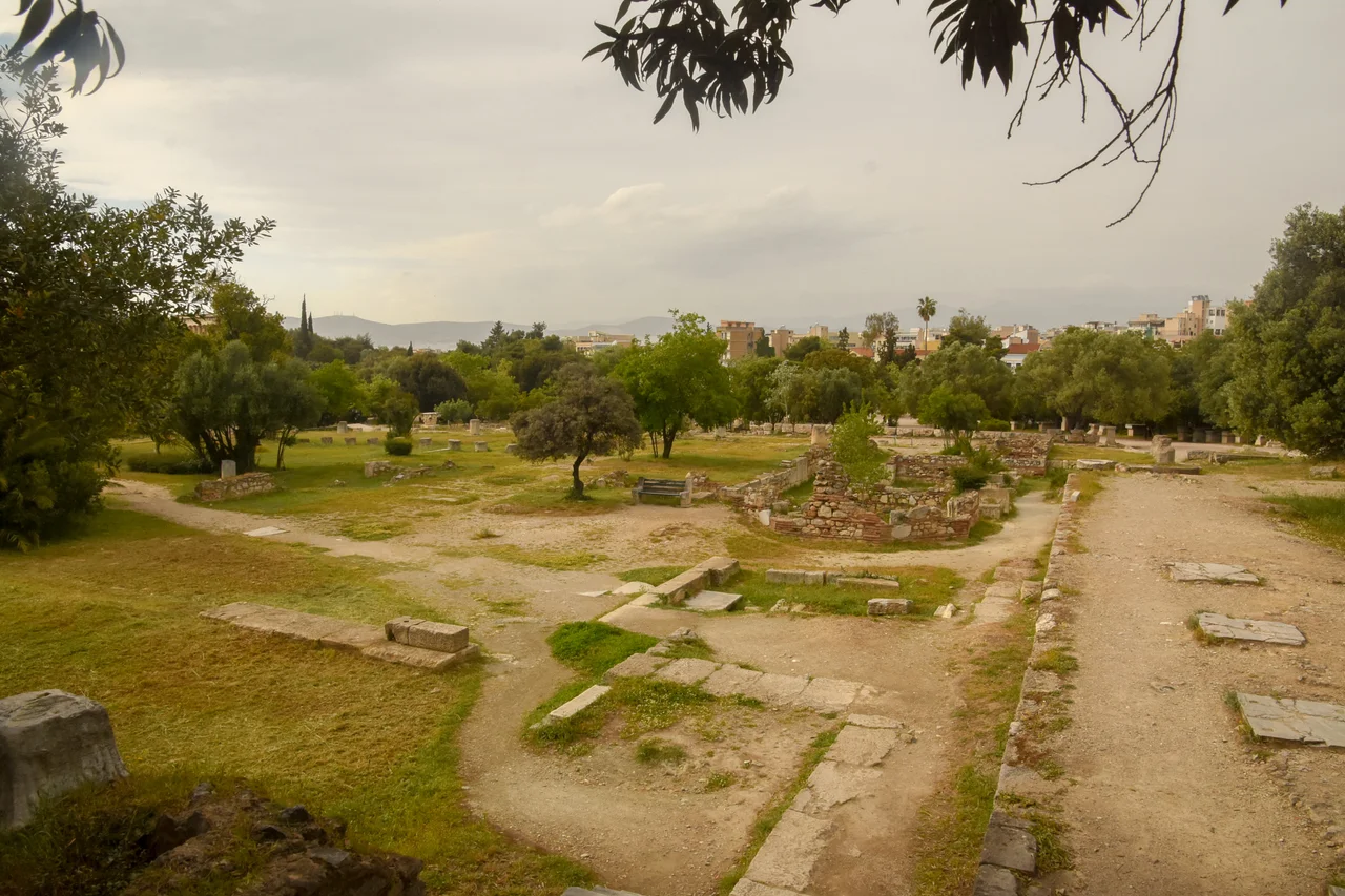 500px provided description: This photo was taken just outside the church of the Holy Apostles, built on the ruins of the Mint and the Nymphaion. To the right, three of the marble slabs of the floor of the East Building are seen. The Temple of Hephaestus is barely seen behind the trees in the left side. [#sky ,#tree ,#plant ,#ruins ,#Greece ,#Athens ,#Attiki ,#Temple of Hephaestus ,#Hephaisteion ,#Theseion ,#Church of the Holy Apostles ,#East Building ,#Ancient Agora of Athens ,#Hephesteum ,#Agora of Athens ,#Archaea Agora of Athens ,#Theseum]