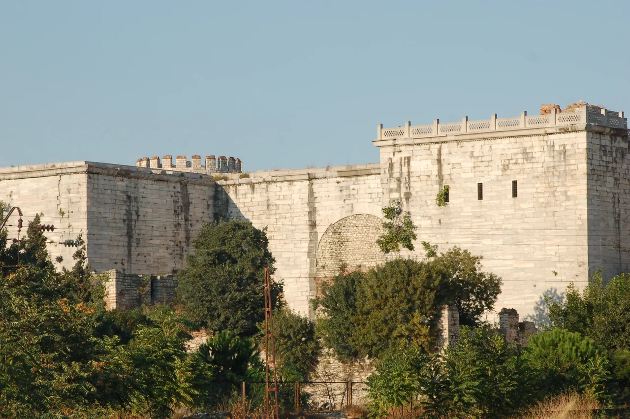 early 21st century photograph of the Golden Gate in the Theodosian walls of Constantinople. Photograph taken from outside the walls from a side angle given the inaccessibility of the outside if the Gate to visitors (front view obscured by forest at the back of a graveyard).