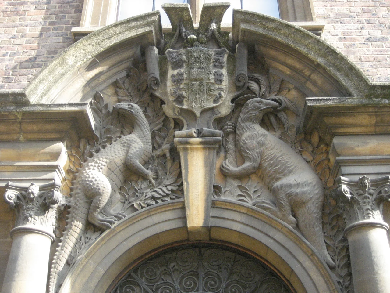 Relief of two prehistoric creatures acting as heraldic supporters to the arms of the University of Cambridge (an Iguanodon on the left of image and a Megatherium on the right) in the building of the Sedgwick Museum of Earth Sciences, University of Cambridge, Cambridge, England (UK).