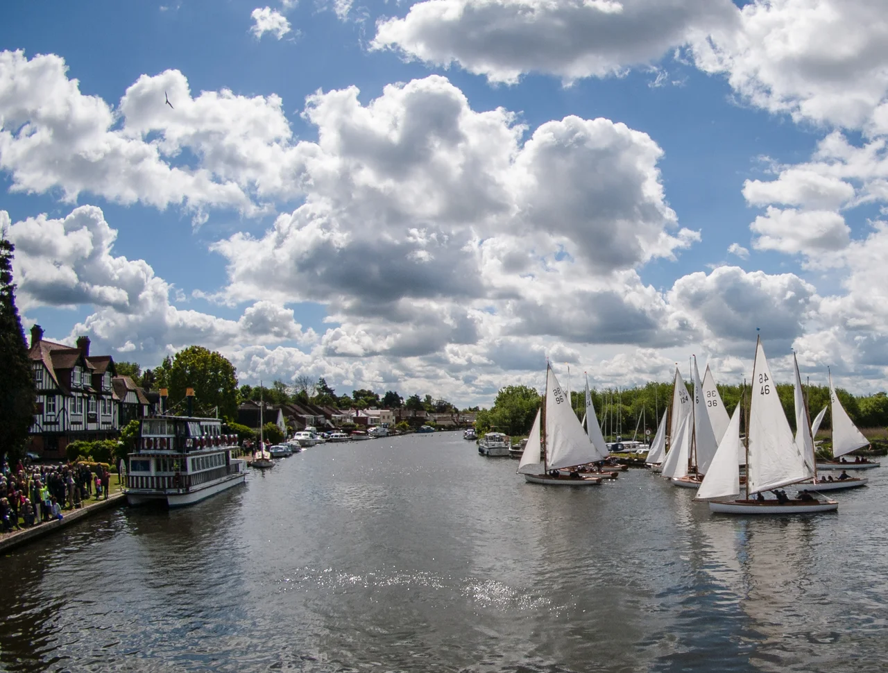 Crowds line the River Bure for the start of the 55th Three Rivers Race at Horning, Norfolk on 30 May 2015. Organised by Horning Sailing Club, this 24-hour event is one of the toughest inland yachting races in Europe. Picture shows the start for the Yare & Bure One Design 'White Boats'. Horning's historic Swan Inn can be seen on the left of the picture. Of the 108 boats entered in 2015, 86 finished in times of between 11 and 18 hours.