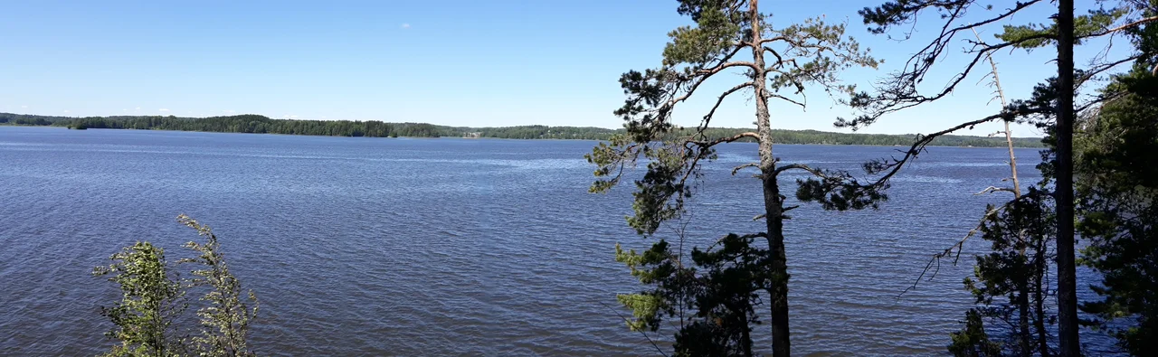 View to the lake Lohjanjärvi from the point of Karkalinniemi peninsula, Karkali Strict Nature Reserve, Lohja, Finland. Tower of Karjalohja Church can be seen on left behind the forest.
