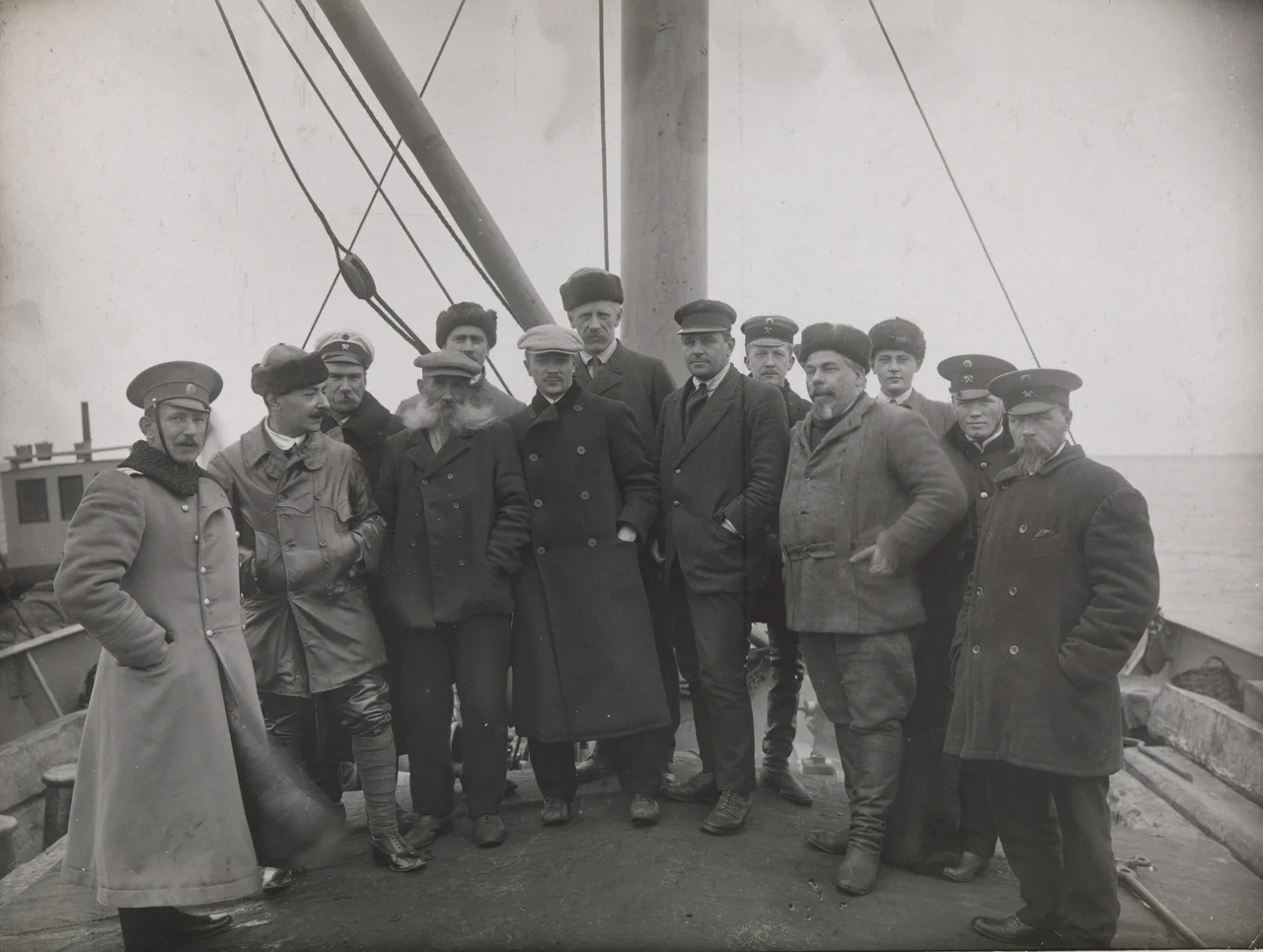 Meeting with officers from the Russian barges at the mouth of the Yenisei River. This was the end of the sea travel to Siberia. Among the people gathered: the crew from the «Correct», a Russian captain from the barge «Turukhansk», and the customs officers. Second from the left, Josef Gregorievitsj Loris-Melikov (secretary at the Russian legation in Norway); fourth for the left the ice pilot Hans Christian Johansen (Johannesen ); behind him, fifth from the left Jonas Lied, sixth from the left probably is Gunnar Christiansen, Lied's managing clerk; seventh from the left Fridtjof Nansen; eighth from the left Capt. Johan Samuelsen; tenth from the left, Stephan Vasilievitsj Vostrotin (gold mine owner from Yeniseisk). After a few days stay, Nansen, Loris-Melikov and Vostrotin continued their journey up the Yenisei River. The ship «Correct» with J. Lied and G. Christiansen unloaded their cargo from barges, and returned to Kristiania. One of the pictures from the journey to Siberia between Aug. 2 and Oct. 26, 1913. Fridtjof Nansen started his trans-Siberian travel on a freighter from Oslo to Yenisei. The journey went through parts of the Northeast Passage, which was to be opened as a shorter trading connection between Western Europe and the Far East.