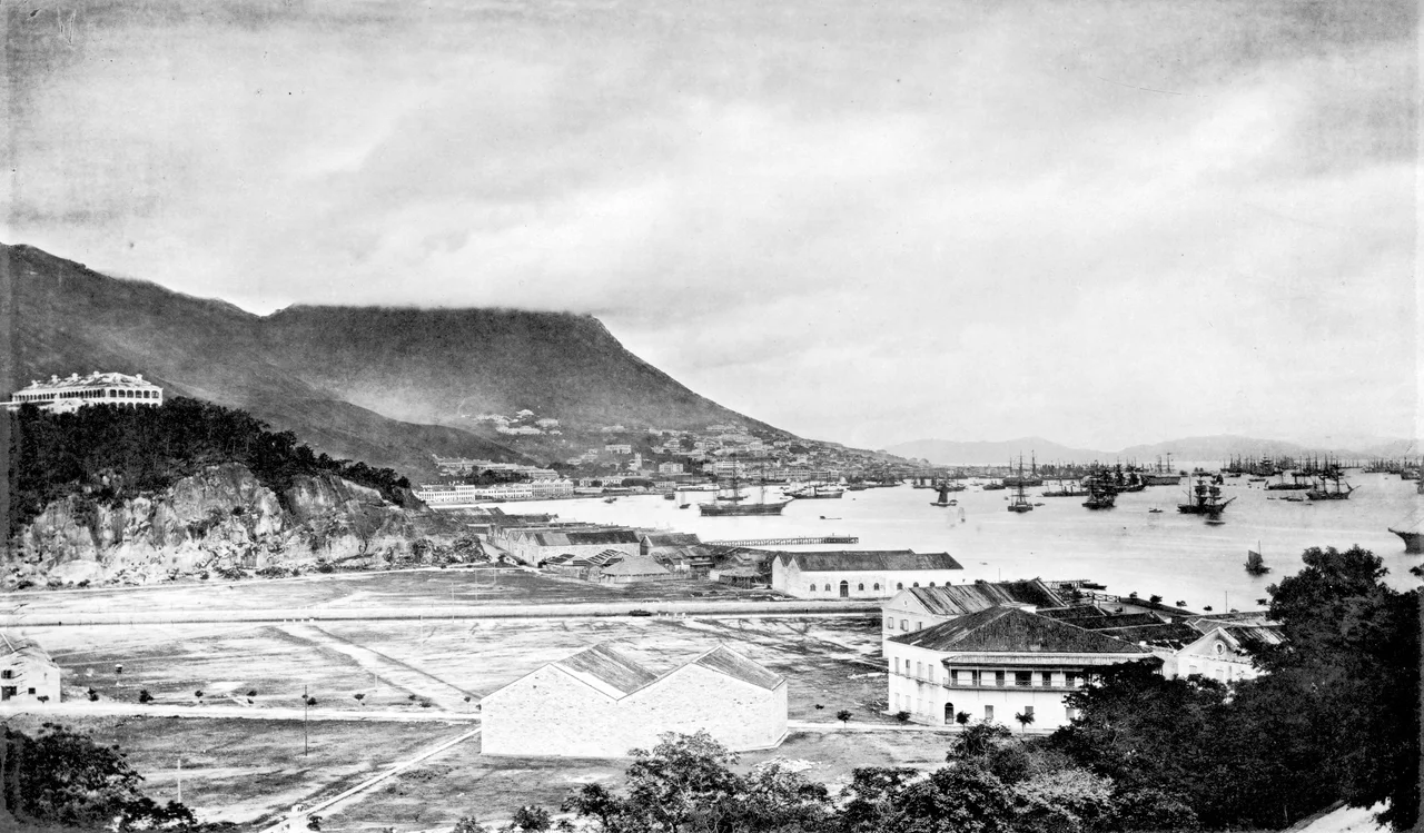 John Thomson: HONG-KONG is one of a group of islands situated a little north of the mouth of the Canton or Pearl river. It is about ten miles long, by four and a-half in breadth, and of igneous formation. From east to west, along its entire length, there runs a central rocky ridge or spine, chiefly composed of granite, and broken up into a series of jagged peaks, whose greatest elevation is 1,900 feet. Viewed from a distance, Hong-Kong may be readily distinguished from the islands which surround it by the bold outlines, and superior altitude, of its hills. The contrast in many cases being as striking as that between the islands of Arran and Bute. The granite in some parts of the island is in a state of disintegration ; but great masses of the solid stone are to be found, and have proved of service in the construction of the forts, the docks, and the city of Victoria. The latter is to the north of the island, on the slope of the hill named Victoria Peak, and faces that portion of the mainland which is known as British Kowloon. The Kowloon coast here, and the northern shore of Hong-Kong, combine to form one of the finest harbours in the world, having a space of over six miles in length by two in breadth, available for the safe anchorage of the largest ships. The view which fronts this page is taken from the residence of Messrs. Jardine, Matheson and Co. at East Point. In the immediate foreground is shown the entrance to Wong-nei-chong or Happy Valley, noted for its picturesque hill scenery, its race-course, and its cemetery for Europeans. The eminence to the left is Morrison's Hill, crowned with a row of substantially built foreign residences, and commanding an extensive and imposing view of the city and ports.
Victoria, with its long line of wharves and warehouses, its public buildings, and its private residences in elegant rows, is seen resting on the slope of the lull; while characteristic masses of fleecy cloud are wrapped around the peak above. The masts of the shipping, which rise like a forest about the Victoria promontory, may give the reader some conception of the magnitude of our trade at Hong-Kong. By the treaty of Nankin, in 1842, the island was ceded to the British, and was erected into a colony on the 5th of April, 1843.
Previous to the above dates Hong-Kong was as barren and uninteresting as the islands around it at the present day, where one can find nothing more than a few fishing hamlets, enjoying, however, a degree of prosperity unknown before the advent of the British flag. There is only one ancient privilege the loss of which these villagers, it may be, deplore. Those among them who wore the peaceful garb of fishermen used to vary their pursuits, a little more than twenty-five years ago, by engaging in piracy when opportunities occurred. So confirmed is their relish for buccaneering, that, in spite of the heavy penalties now imposed upon the crime, it has not yet been completely rooted out ; and, although much rarer, we still hear of piratical outrages in or near the very harbour of Hong-Kong. Such notices as the following, not unfrequent during the early history of the colony, are happily seldom met with in the present day : — " In March, 1846, a large body of pirates, some eighty in number, plundered the village of Shek-pai-wan," now known to foreigners as Aberdeen, and boasting an extensive dock. " On the 25th of April, 1854, a severe encounter took place between the police and a gang of hill robbers at Shek-pai-wan, in which several of the robbers were shot.""Twenty-two piracies are noted in Hong-Kong waters between the 1st November, 1856, and 15th January, 1857.“
On the 15th January, 1857, an attempt was made to poison the entire foreign community by the Chinese bakers, who introduced arsenic into the bread. Had the drug been admixed in smaller quantities, an awful catastrophe might have taken place. But the presence of the poison was so easily detected, that public criers, promptly sent round, were in time to prevent many from taking the bread. These bakers had, no doubt, been bribed by more influential parties ; but we believe few, if any, of the offenders were punished for the crime. When to the foregoing calendar of horrors we add the malignant fever, which swept off foreigners by the score, due, as was supposed, to the noxious gases exhaled from the surfaces of decomposed granite laid bare during the erection of the city, we must admit that the island fairly earned its reputation as the grave of Europeans.
Both it and the native inhabitants have undergone marvellous changes within the last twenty-five years. A splendid town has been built out of its barren rocks ; and the hill-sides are covered with trees, which not only enhance the picturcsqueness of the place, but are of great value in purifying the air, and improving the health of the population. In morality, too, it has undergone a change; though perhaps not quite so marked, as the organization of the police has become more perfect, while the good feeling and interest of the wealthy and respectable class of native residents have been enlisted in the suppression of crime.
The bands of desperate ruffians that used to infest the island are fast disappearing, although Hong-Kong still holds its own in crimes below piracy and assassination. The terrors of the law are insufficient to suppress pilfering and petty larceny, practised among domestic and other servants ; and perjury constantly recurs, as the lower ranks of natives deem it fully as meritorious to benefit their friends by swearing to a lie as it would be criminal to injure them by telling the truth on oath. Under British rule, the population of Hong-Kong had increased from 7,450 in 1841, to 125,504, as returned by the census of 1865.' The resident foreign community is estimated at over 2,000, principally Europeans and Americans ; few, if any, having been born at the place. The majority of these men are engaged in trade, and only reside in Hong-Kong long enough to obtain a competency with which they may retire to their native land. The facilities of transit now afforded by the various lines of steamers render a trip home so inexpensive and expeditious, that those who can afford it frequently avail themselves of a run to the old country ; the more so as the increased commercial activity and competition of the present day have lengthened indefinitely the period of residence necessary for the accumulation of even a modest fortune.