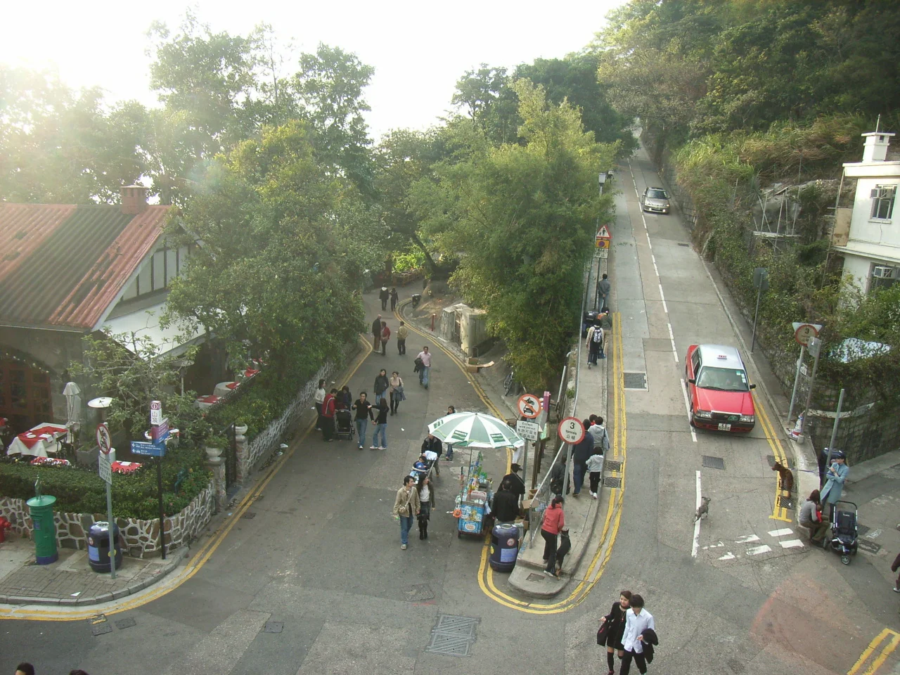 Road junction next to the Peak Tower, at Victoria Gap, on Victoria Peak, Hong Kong.
From left to right:

Peak Road
corner of The Peak Lookout restaurant
Harlech Road (with street vendor)
Mount Austin Road (with taxi)
part of the facade of No. 1 Lugard Road
Lugard Road.
Photographer and author is ParkerStarS.