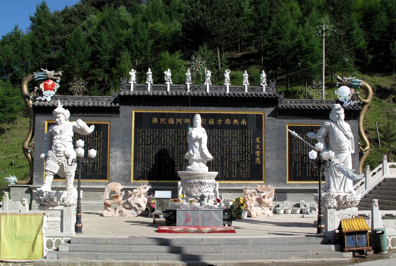 Baiyun Si, on Wutai Shan
The number of White Cloud (Bai Yun) temples in China includes a popular one in Beijing, and another in nearby Dai County. However, the temple seen here is neither of those; it is located on Mount Wutai, at the base of the South Peak. Emperors of the Qing dynasty used to stay here when they were on pilgrimage, and now it has been newly rebuilt (1995) under the direction of Abbot Changxi.
The temple's screen wall, covered with a long dedicatory inscription, forms the backdrop to an outdoor altar of Dishui Guanyin tended by guardians: one each to the left and right of the Bodhisattva, and a set of eight vidyarajas that are perched atop the wall.